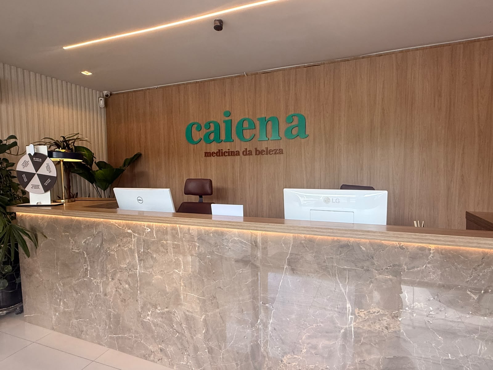 Recepção da Clínica Caiena com balcão em mármore e painel de madeira